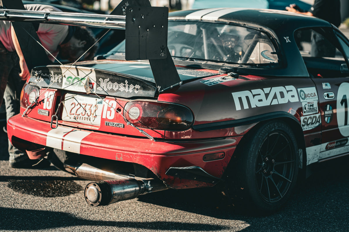 Red Mazda motorsport race car with rear wing, photographed by Drake, Unsplash